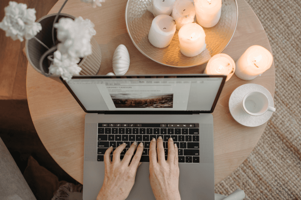 Person working on a laptop surrounded by candles, creating a calming space to manage goal setting anxiety and perfectionism.