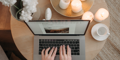 Person working on a laptop surrounded by candles, creating a calming space to manage goal setting anxiety and perfectionism.