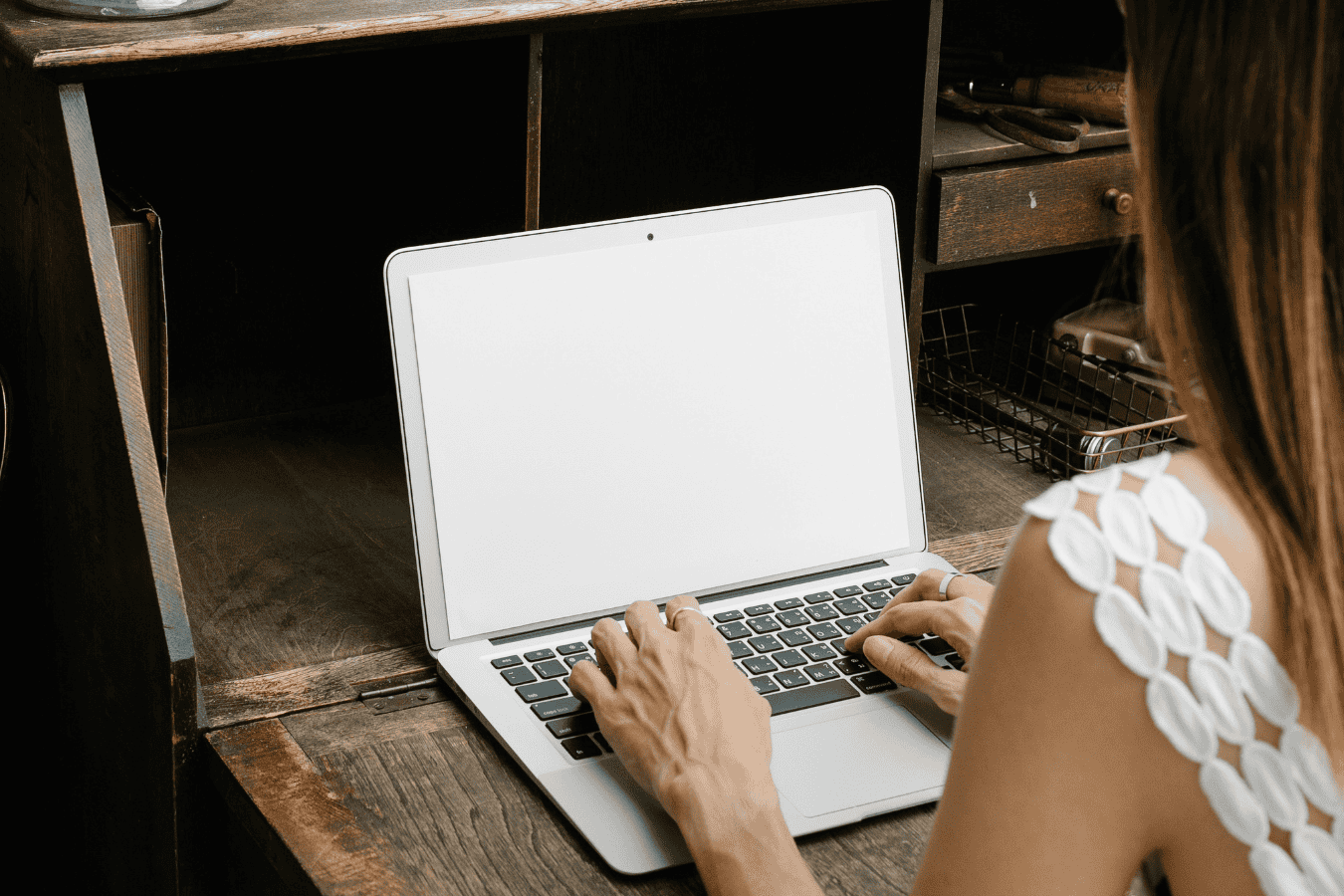 Woman typing on a laptop with a blank screen, representing high achiever burnout.