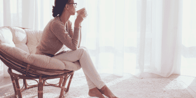 Woman sipping coffee in cozy chair, wondering 'Do I need therapy?'