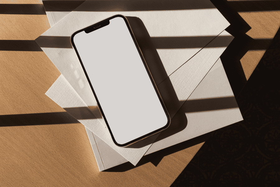 Flatlay of a phone on top of papers, symbolizing the constant pull of productivity addiction in daily work life.