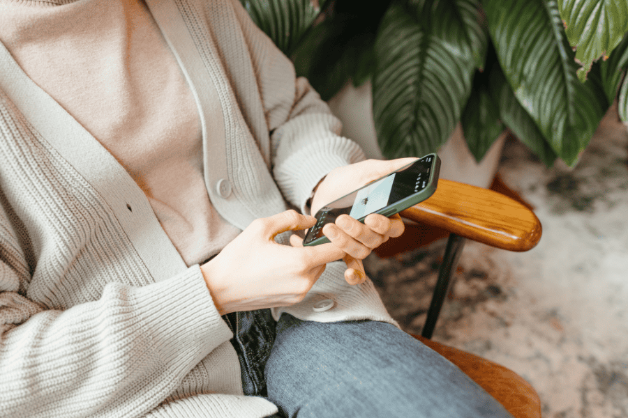 Person sitting in a cozy chair looking at their phone, possibly searching 'Do I need therapy?