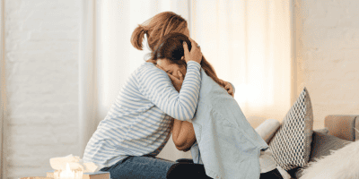 Two people, with one providing support to the other, highlighting the power of asking for help.
