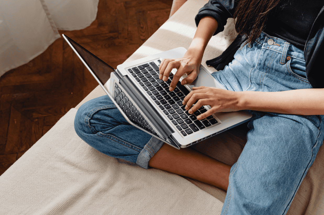 A woman typing on a laptop, exploring the topic of therapy vs self-help and considering the best path for personal growth.