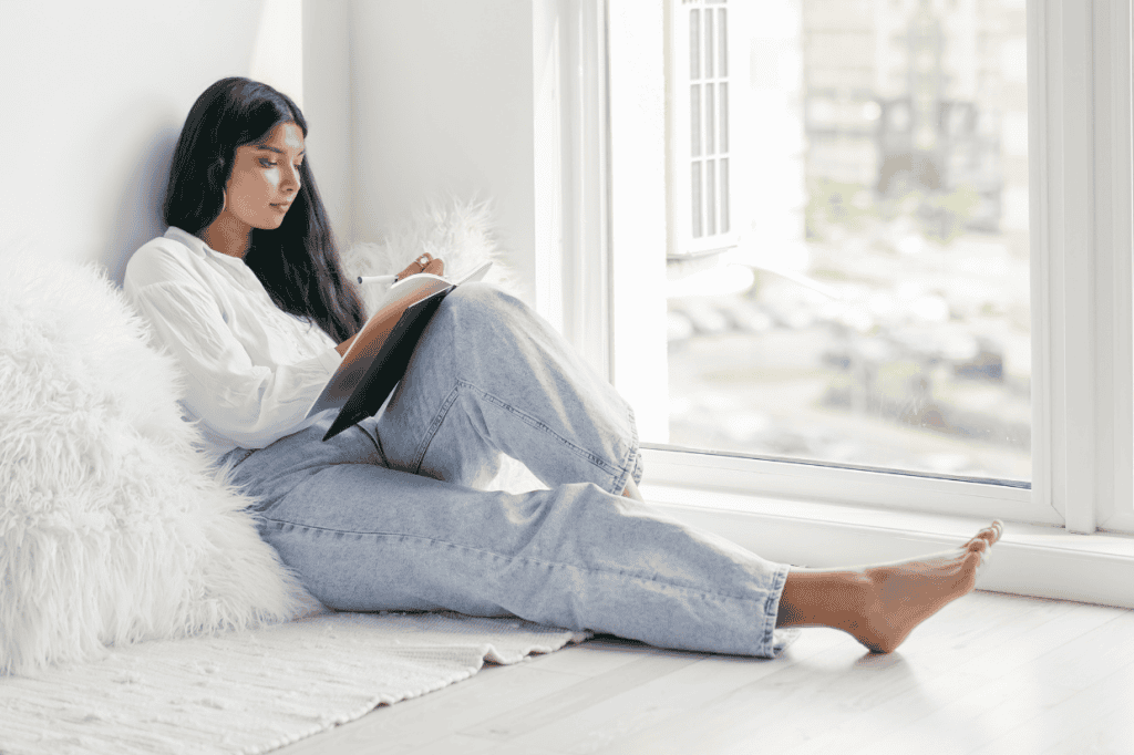 A woman sitting and writing, reflecting on the difference between therapy vs self-help and how each can support personal growth.
