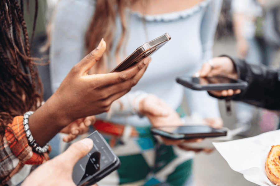 Group of friends on their phones, a common moment where social media comparison often happens without thinking.