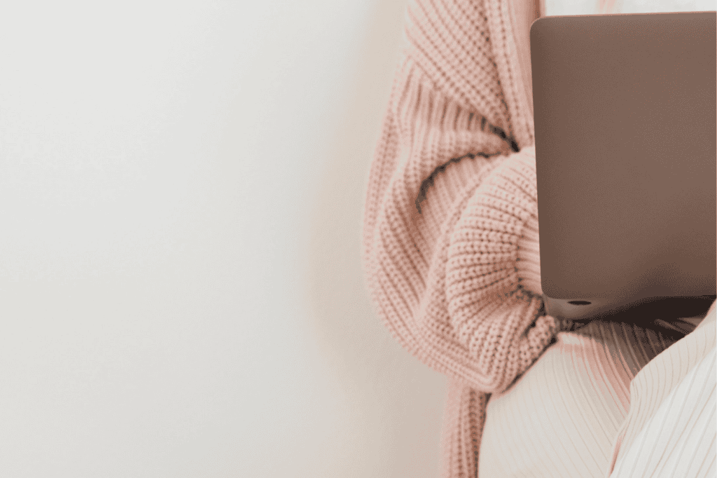 Individual wearing a pink sweater working on a laptop, highlighting practical time management strategies for busy professionals.