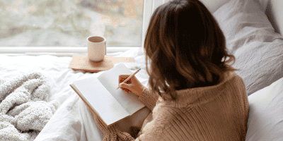 Woman writing in a notebook while thinking about personal growth and moments where they didn’t meet goals this year.