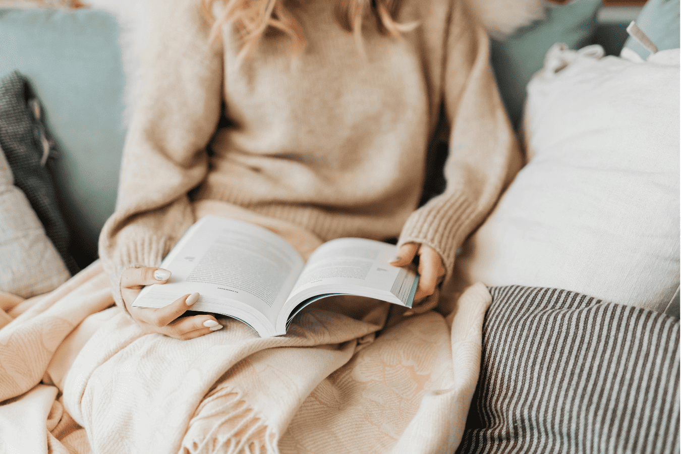 Woman curled up with a book, reflecting on end-of-year feelings and the belief that they didn’t meet goals.